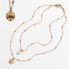 Two dainty necklaces with pendants, one with a silver finish and the other with a gold finish. Both have a chain link design and feature a circular pendant with the phrase 'I am enough' and a heart symbol respectively.