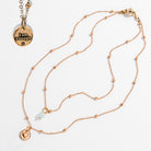 Two dainty necklaces with pendants, one with a silver finish and the other with a gold finish. Both have a chain link design and feature a circular pendant with the phrase 'I am enough' and a heart symbol respectively.