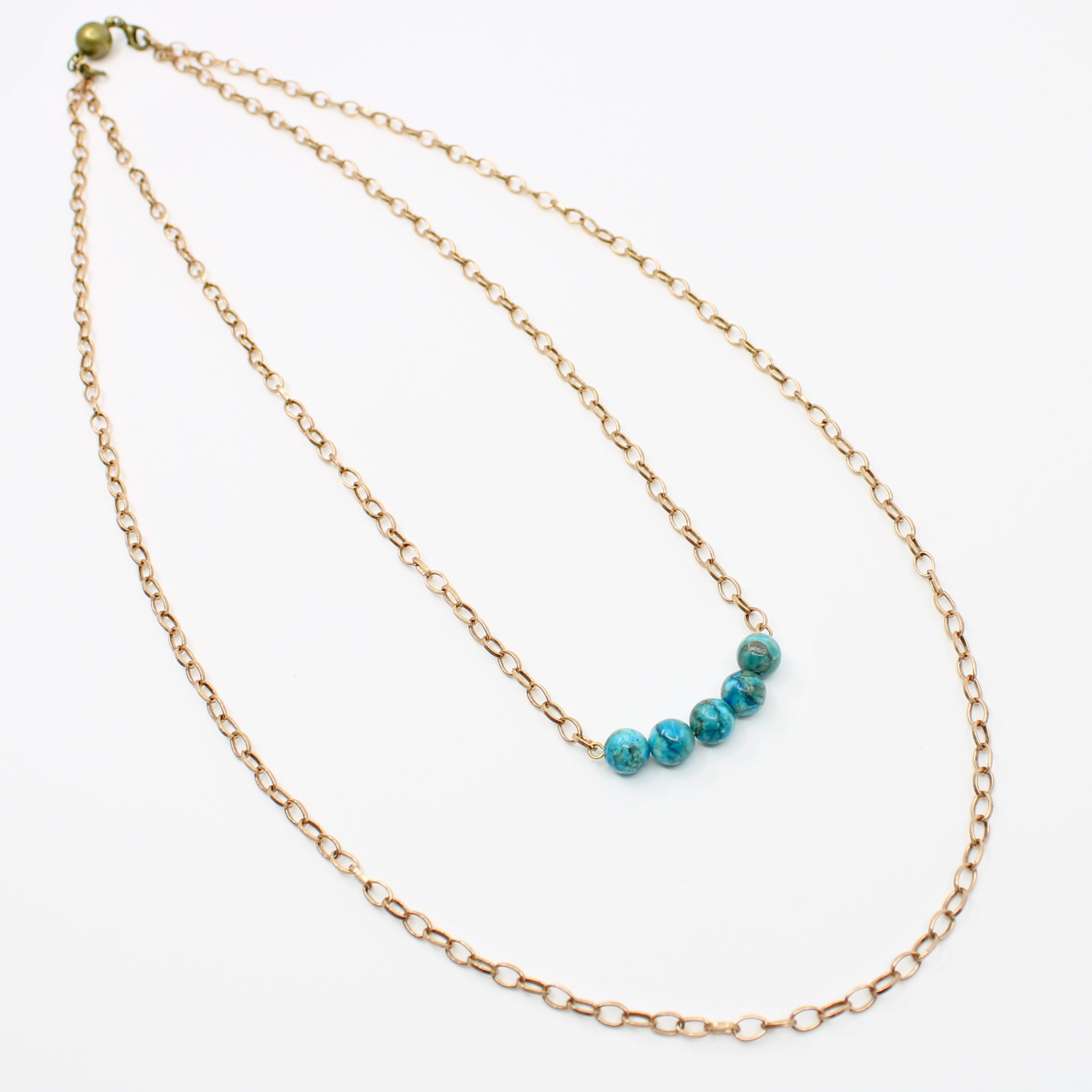 Stainless steel necklace featuring a gold chain with a row of five Aqua Terra Jasper beads, beautifully marbled in blue, set against a pristine white background. Perfect for layering.