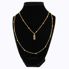 Gold necklace with a pendant on a black mannequin bust