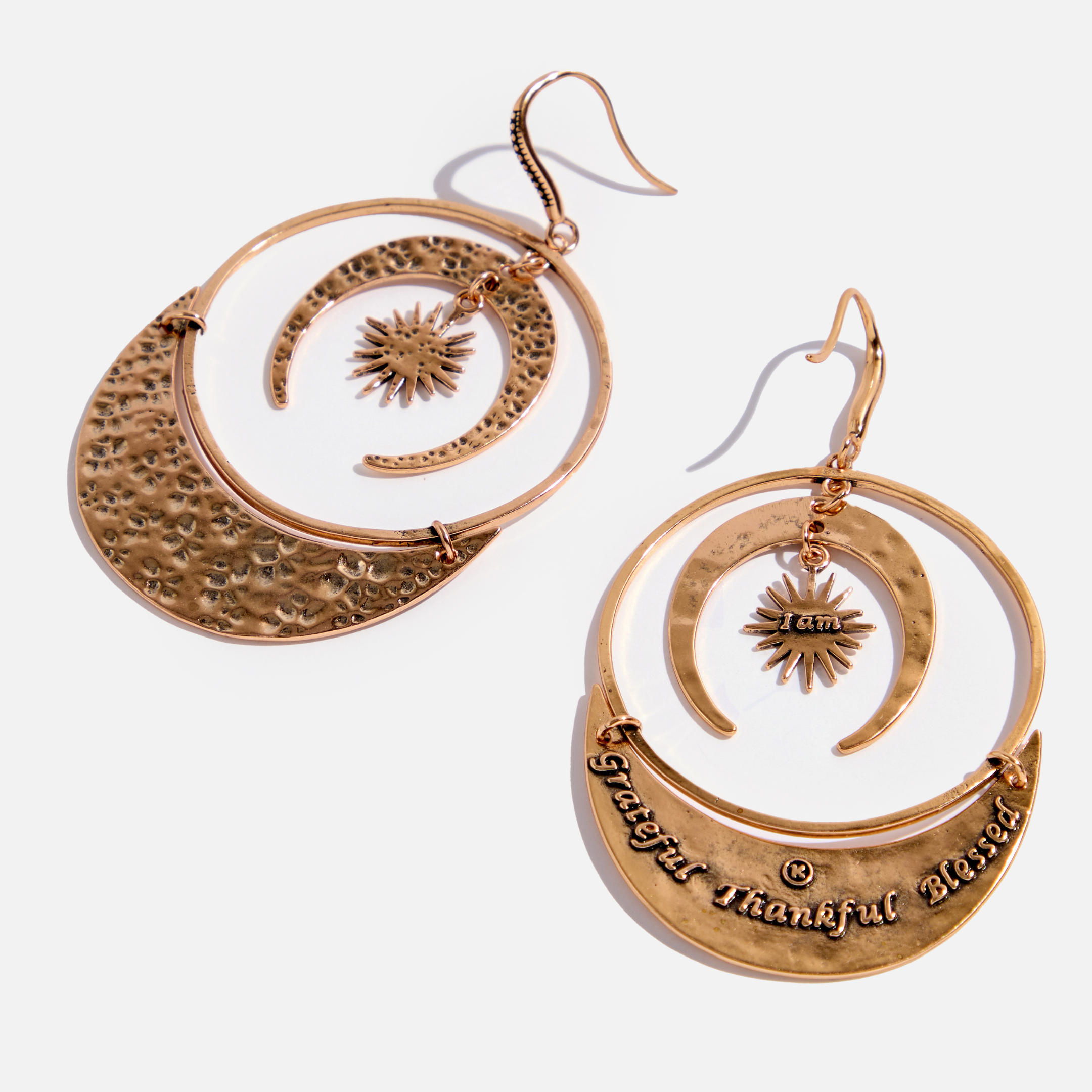 A pair of drop earrings with a hammered texture and a message inscribed on one side, available in two colors: one with an antique gold finish and the other with an antique silver finish, both featuring a star and moon design.