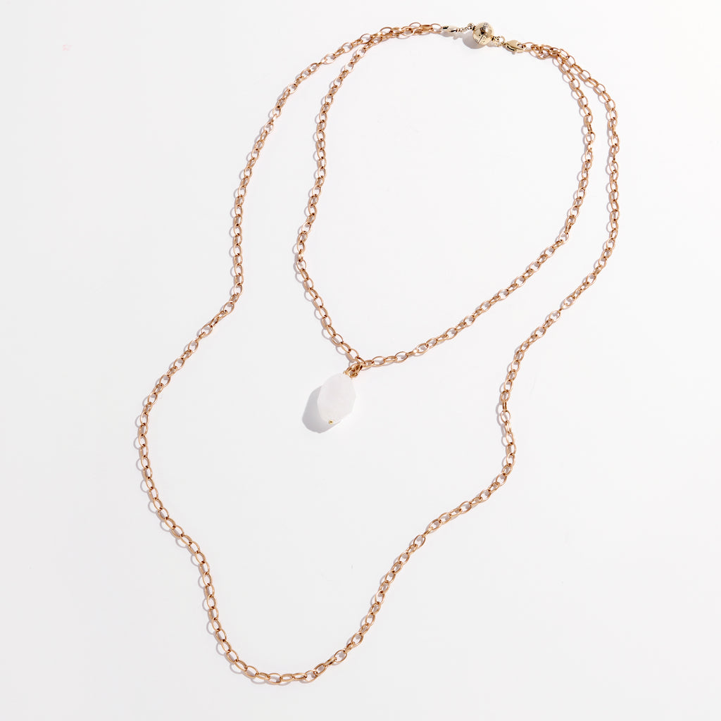 Handmade jewelry at its finest, this gold chain necklace features a white stone pendant elegantly displayed against a white background.