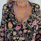 Person wearing a floral dress with a long beaded necklace