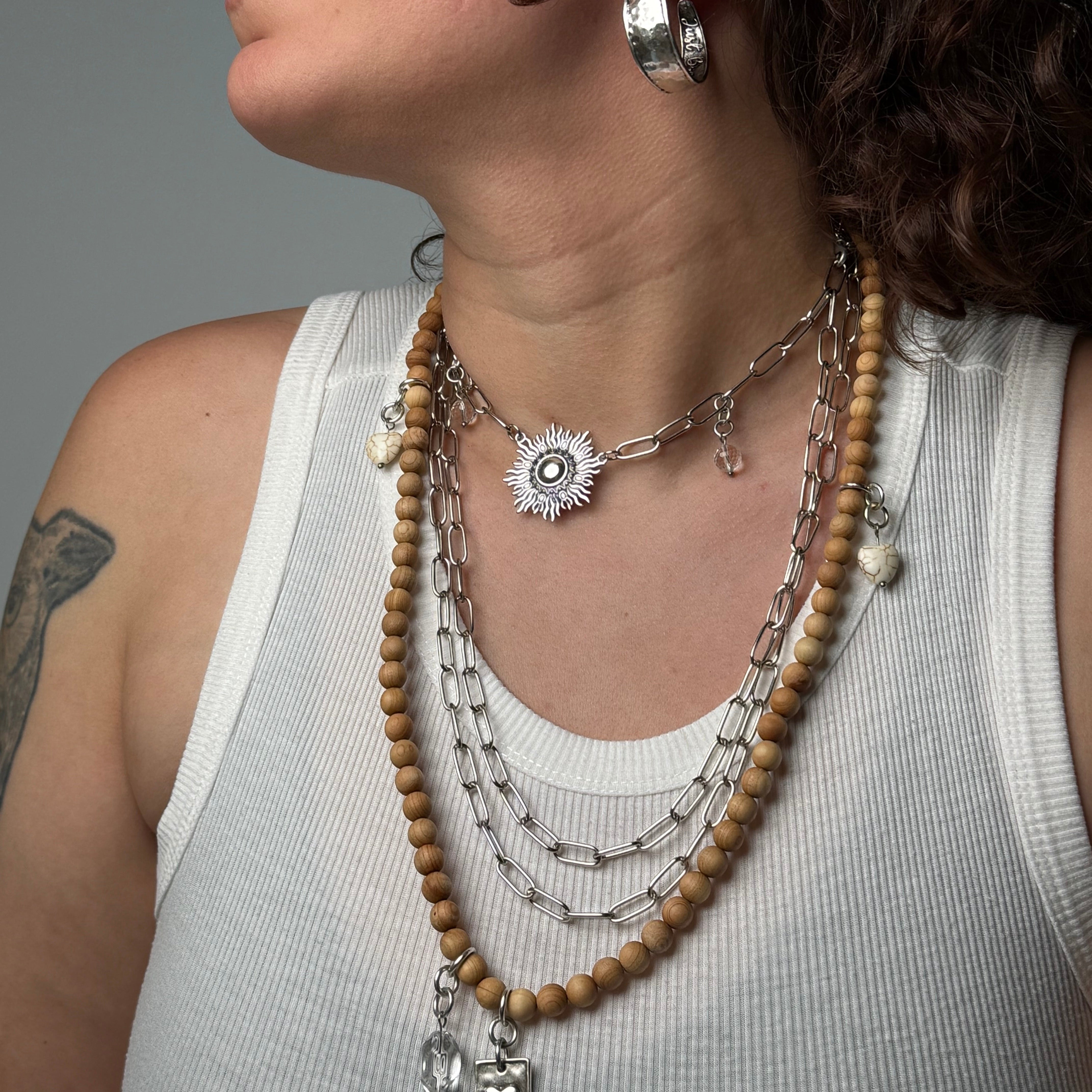 Close-up of a person wearing a beaded necklace and earrings on a gray background