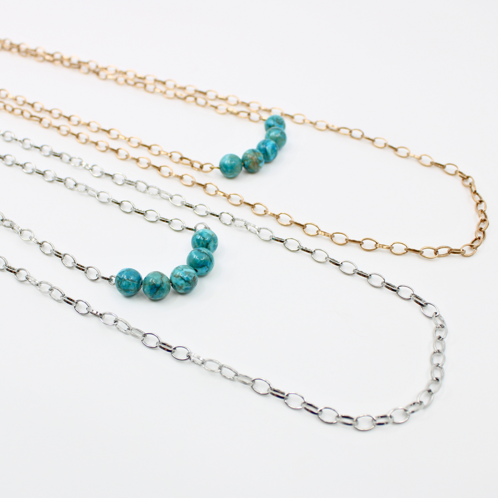 Stainless steel necklace featuring a gold and silver chain with a row of five Aqua Terra Jasper beads, beautifully marbled in blue, set against a pristine white background. Perfect for layering.