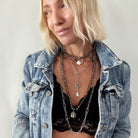 Woman wearing a denim jacket and layered necklaces against a plain background