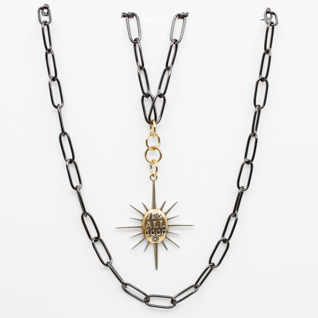 sunburst pendants on chains; one says Its all good and features a mix of silver and gold tones. both on a sleek gunmetal chain, offering a modern twist with its subtle magnetic clasp for easy wear.