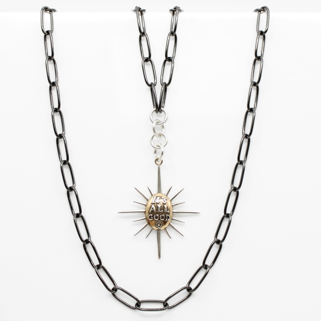 sunburst pendants on chains; one says Its all good and features a mix of silver and gold tones. both on a sleek gunmetal chain, offering a modern twist with its subtle magnetic clasp for easy wear.