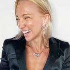 Woman wearing a black blazer with a necklace and earrings on a white background