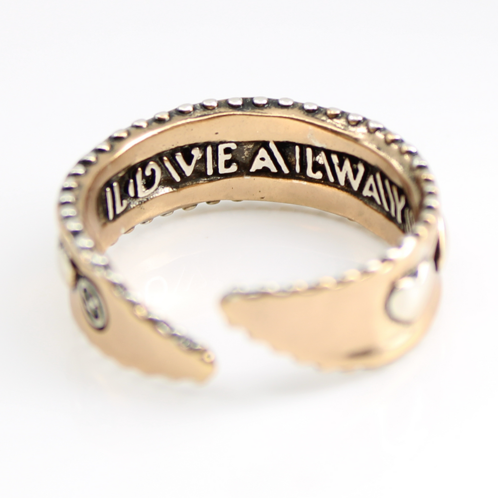 A close-up image of a  textured, mixed-metal ring with an inscription on the inner band reading LOVE ALWAYS. The adjustable ring features a GOLD finish and a scalloped edge, set against a plain white background.