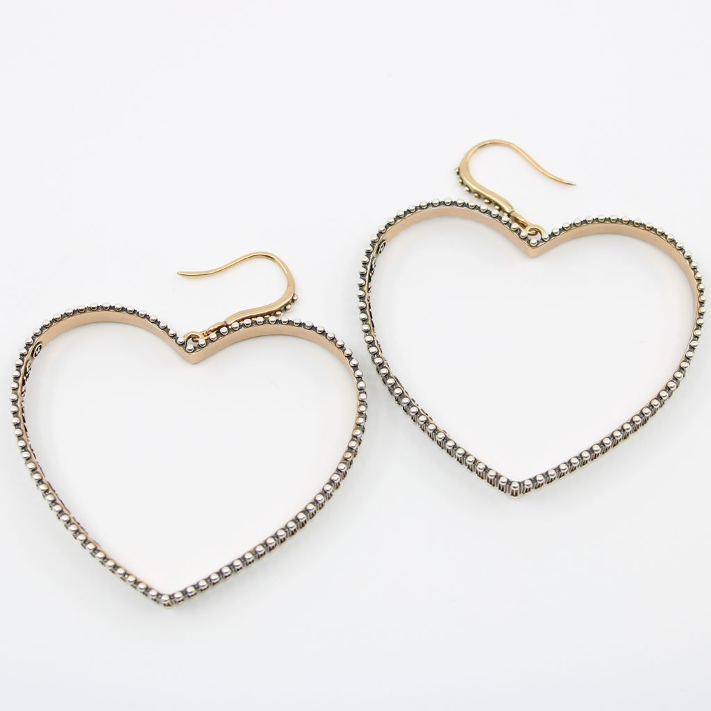 Pair of heart-shaped hoop earrings with a delicate gold-tone frame and an outer edge adorned with small, metallic bead details. The earrings have a hook-style fastening.