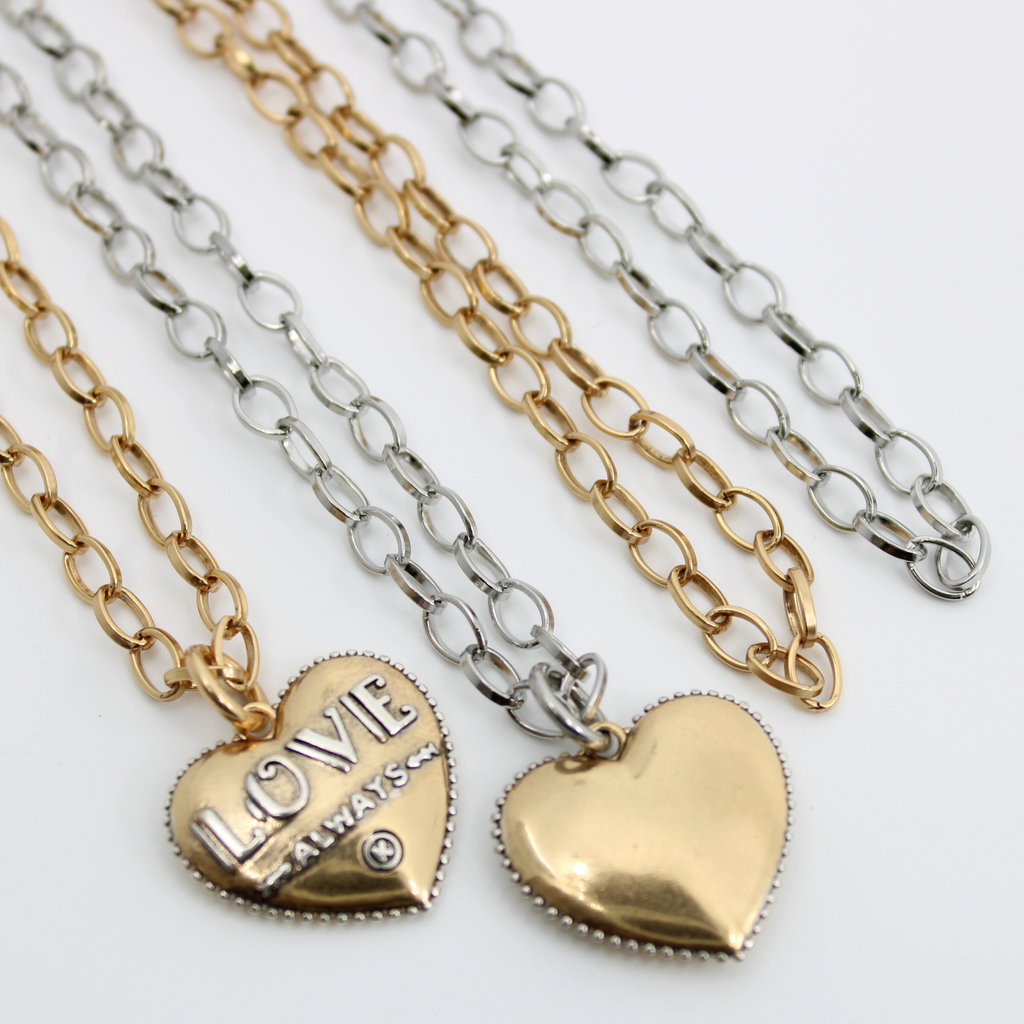 mixed metal chain necklace with heart pendant. 2 chain necklaces, featuring durable stainless steel, in gold or silver with 3D heart-shaped pendants. One side of pendant reads LOVE ALWAYS, while the other is smooth. The chains are beautifully displayed side by side.