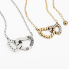 Two heart-shaped necklaces, one silver and one gold, on a white background.