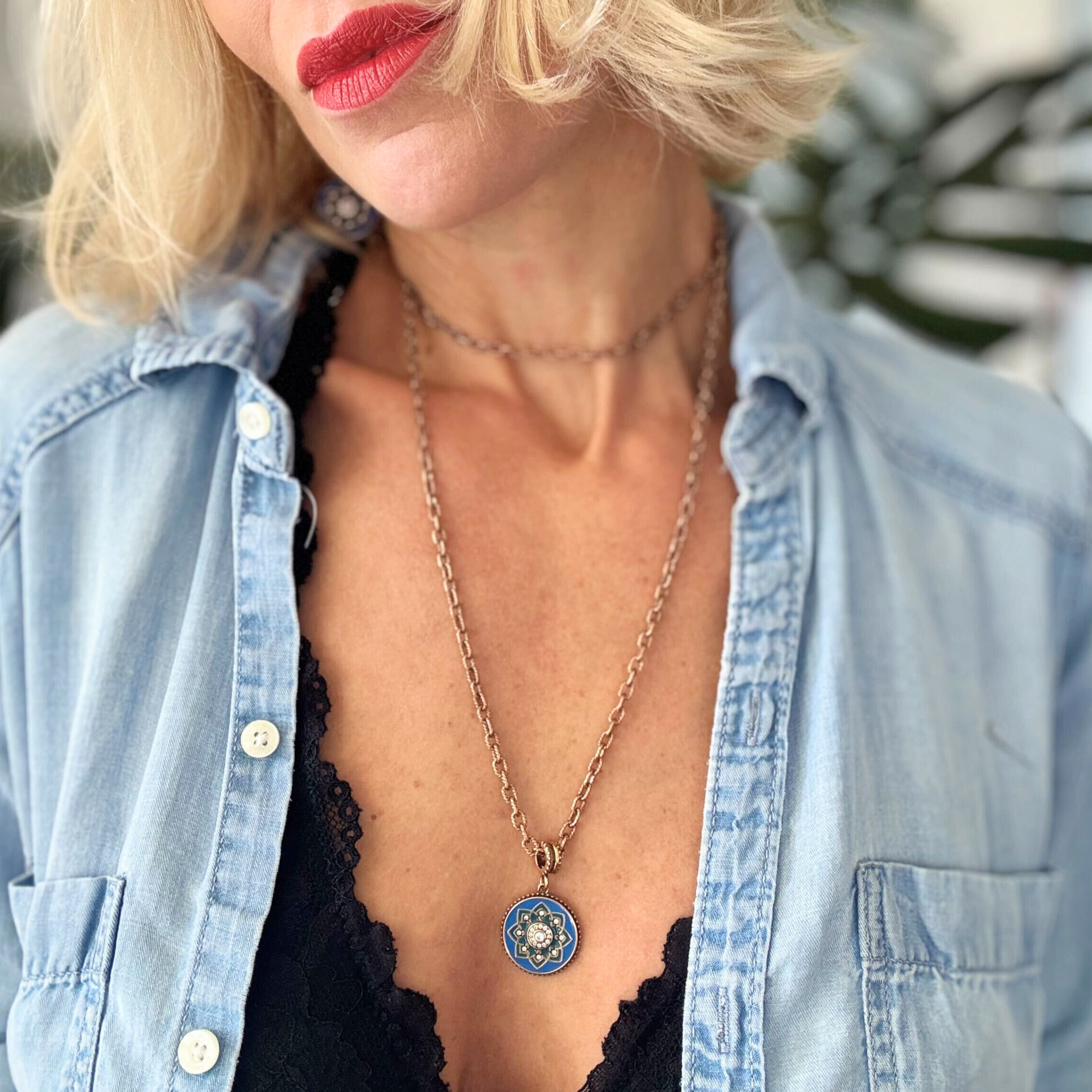 Woman wearing a denim jacket and necklace with a blue pendant.