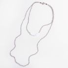 Two layering chain necklaces with pearl accent stones, one plated in gold and the other in silver, displayed against a white background.