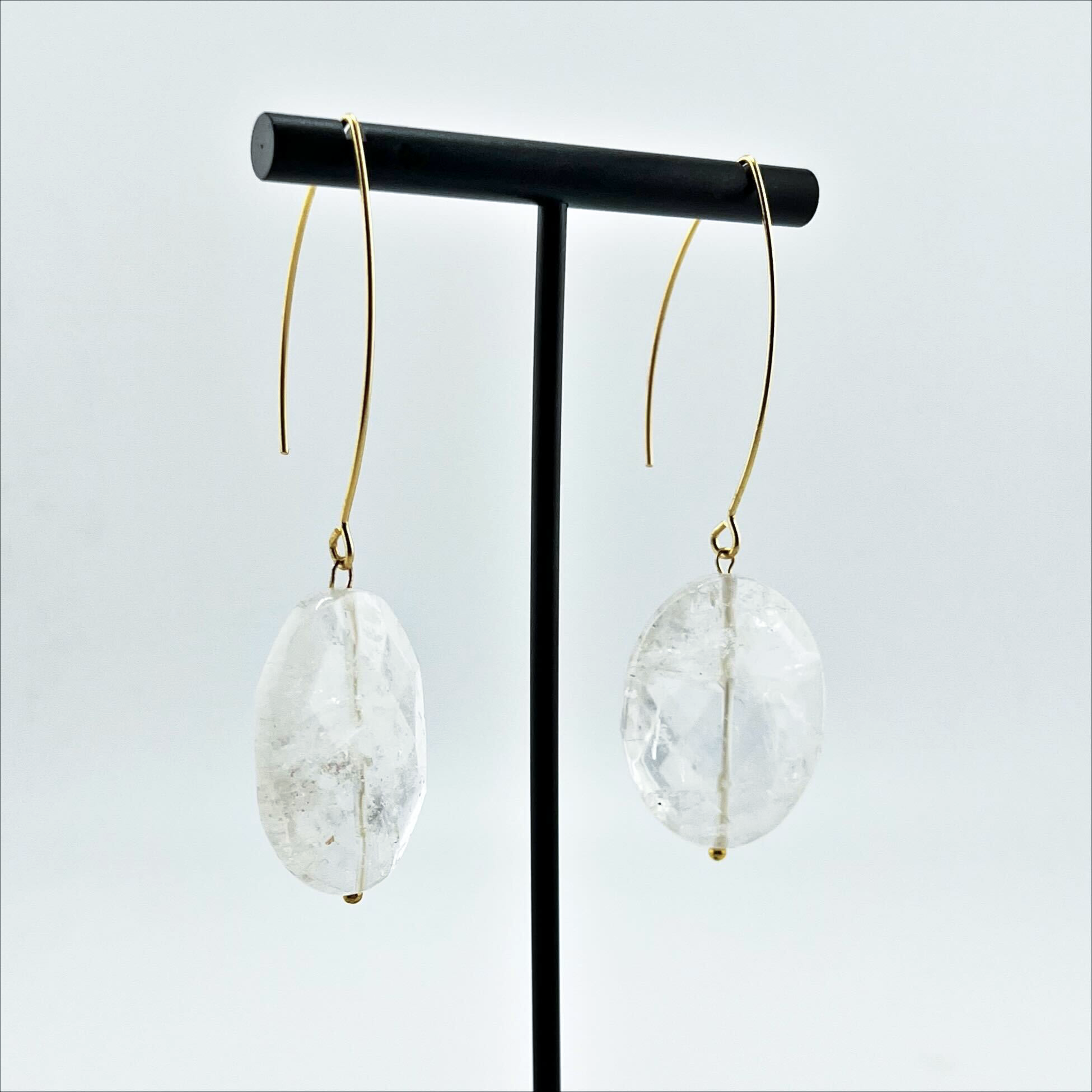 A person wearing large stone drop earrings with a V-shape wire earring holder.