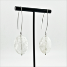 A person wearing large stone drop earrings with a V-shape wire earring holder.