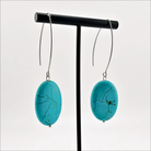 A person wearing large stone drop earrings with a V-shape wire earring holder.