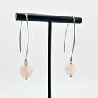 A person wearing small stone drop earrings with a V-shape wire design in a colorless setting.