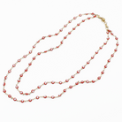 Long necklace with red and gold beads on a white background
