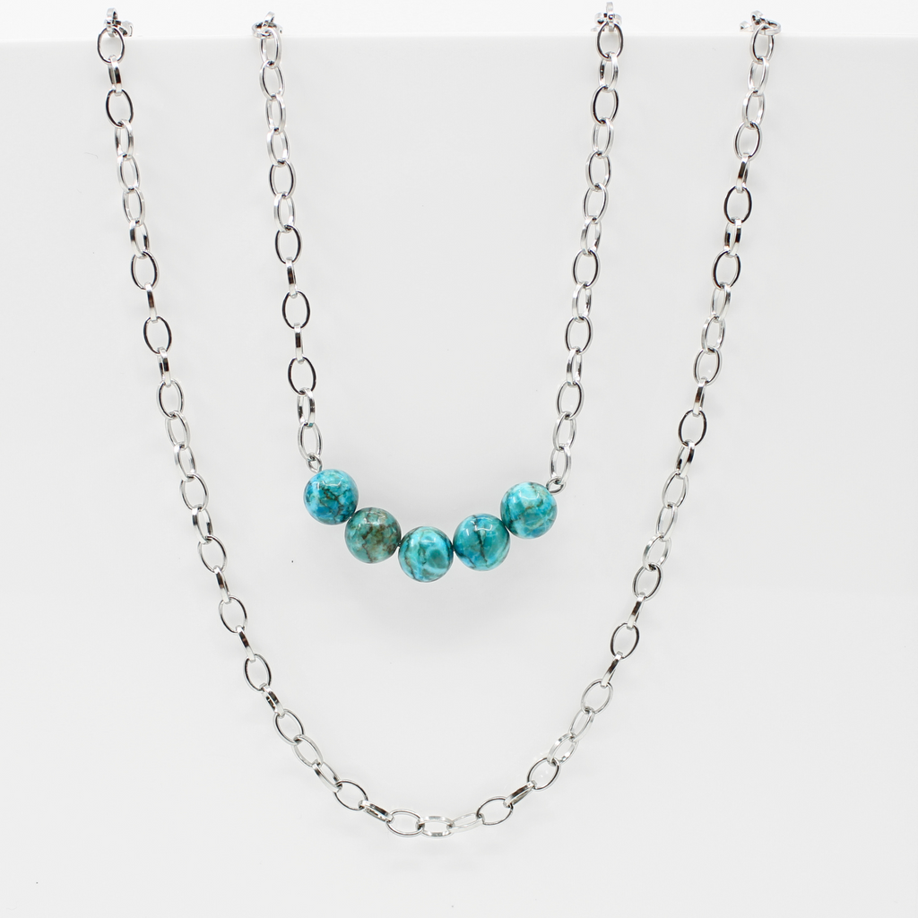 Stainless steel necklace featuring a silver chain with a row of five Aqua Terra Jasper beads, beautifully marbled in blue, set against a black velvet bust. Perfect for layering.