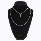 Silver necklace with a pendant on a black mannequin bust against a white background