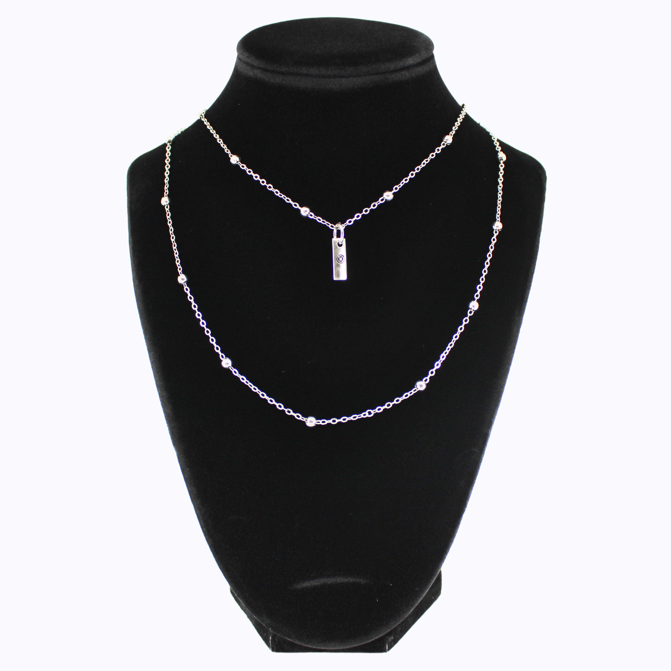 Silver necklace with a pendant on a black mannequin bust against a white background