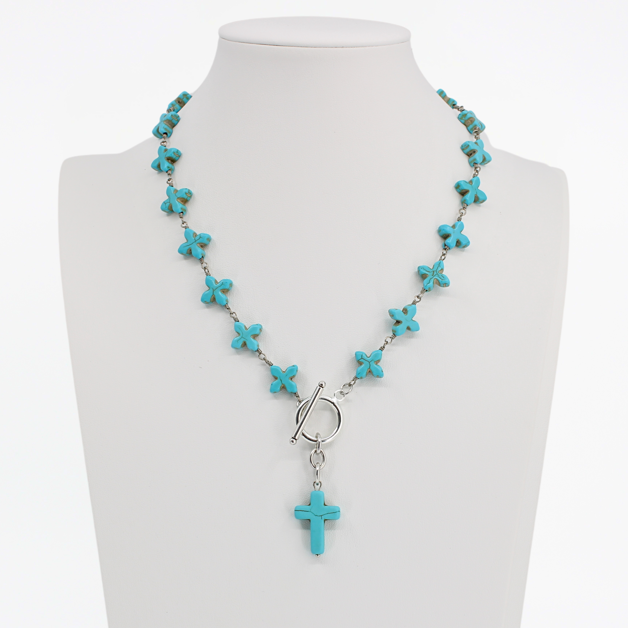 Turquoise cross necklace on a mannequin with a white background