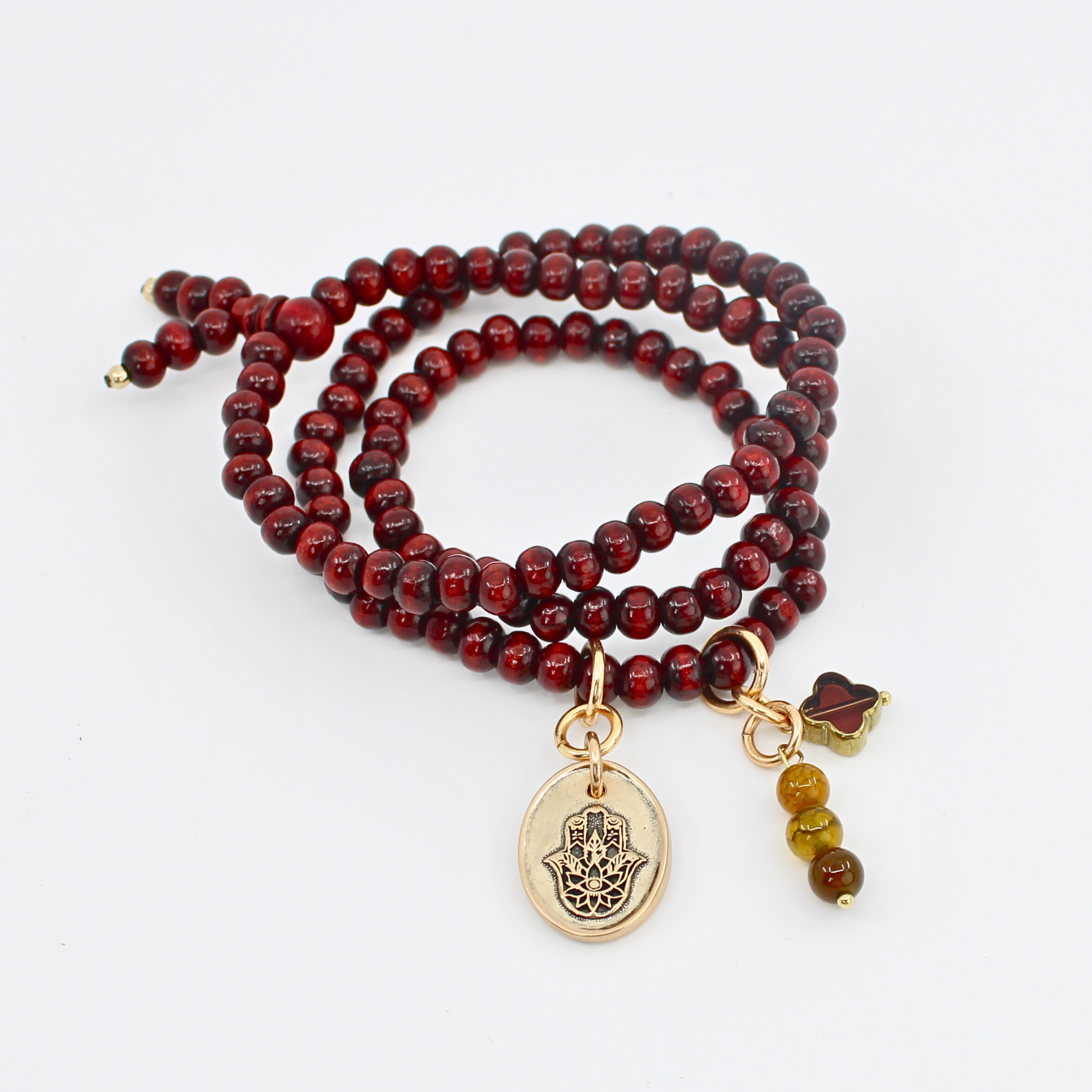 Red beaded bracelet with gold charm and additional beads on a white background