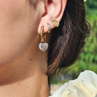 Close-up of an ear wearing gold hoop earrings with a blurred green background