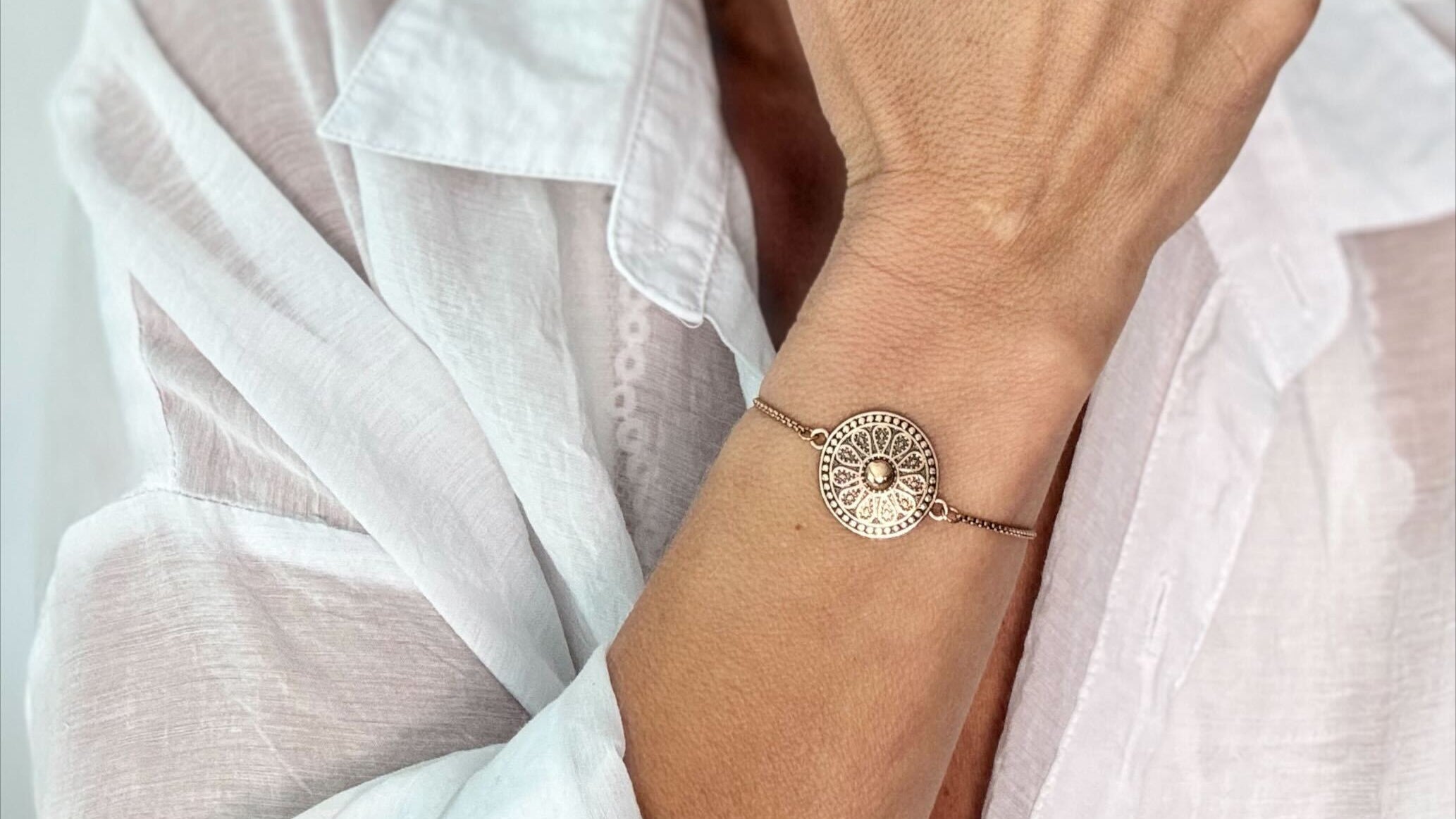 Woman wearing a gold bracelet and ring, with a blurred background