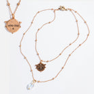 Gold necklace with pendant and pearl drop on white background