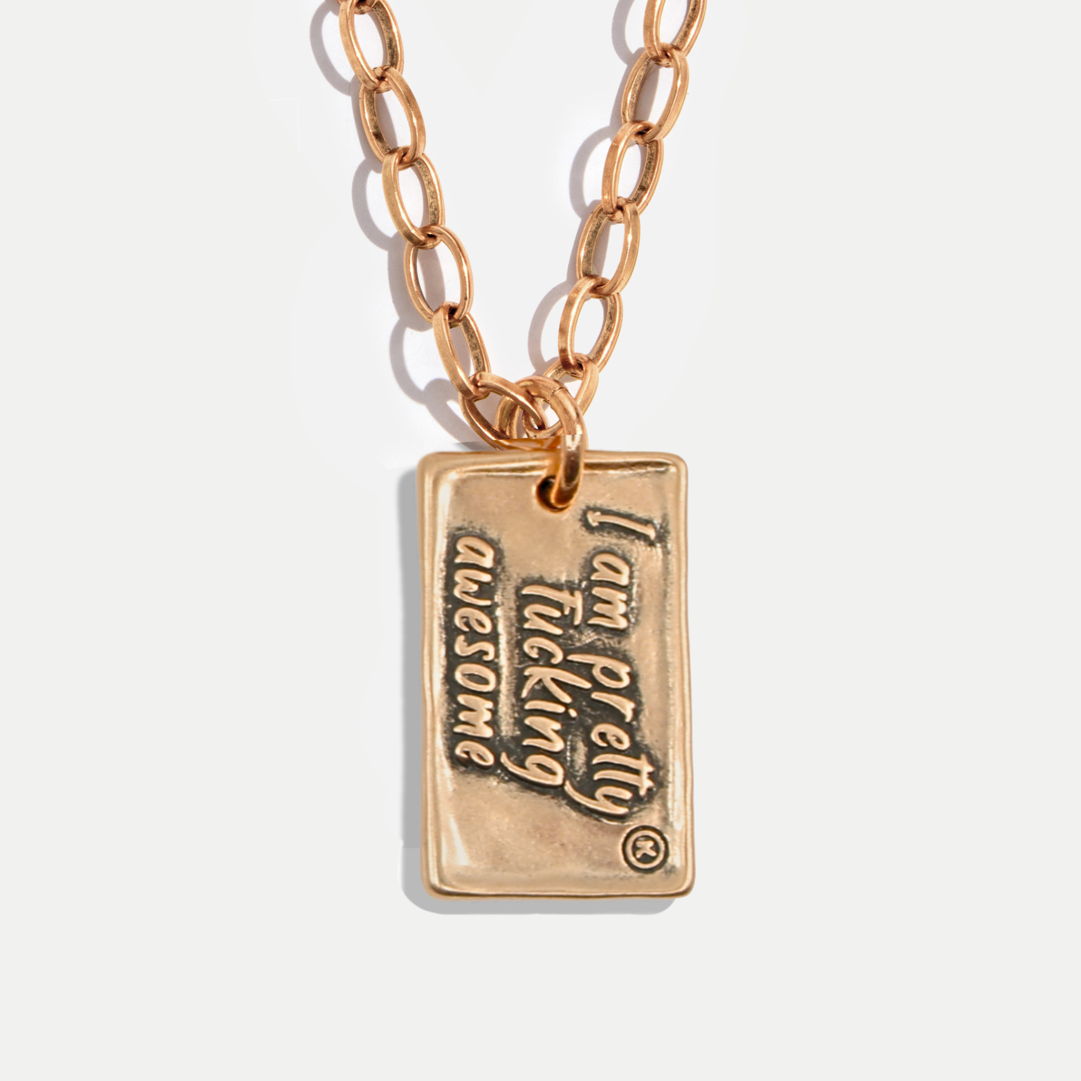 Gold necklace with a pendant that reads 'I am pretty fucking awesome' on a light background