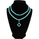 multiple colorful beaded boho wrap bracelets in 4 bright colors made with howlite beads. this image shows the turquoise blue one on a black bust worn as a necklace