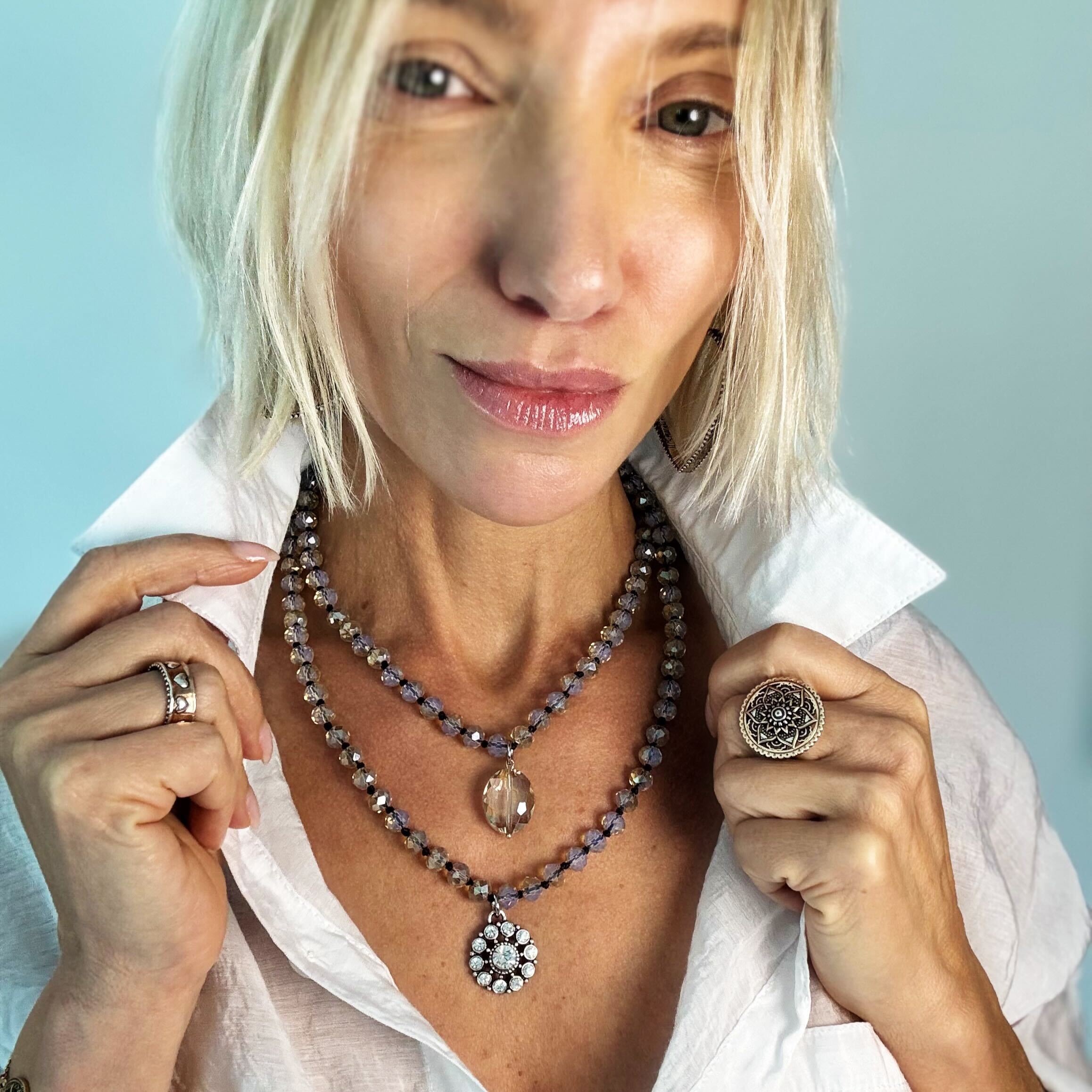Woman wearing a necklace and rings against a light blue background