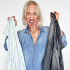Woman holding two shirts, one light blue and one dark gray, against a white background