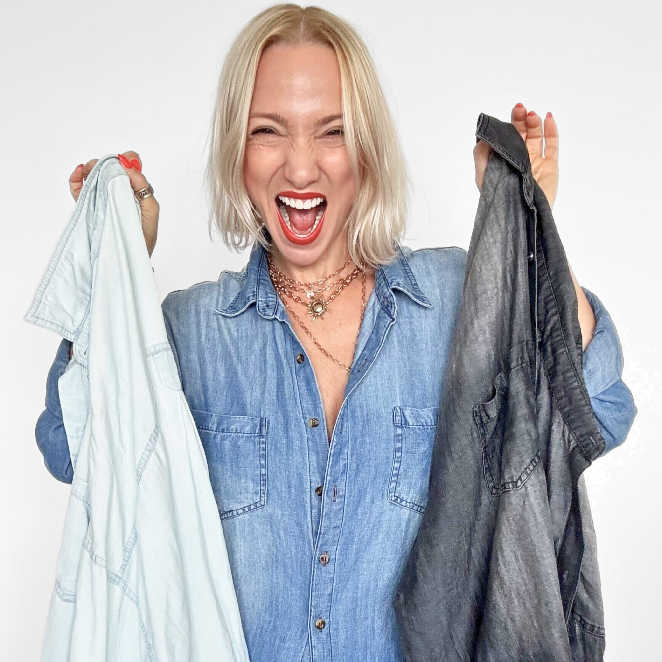 Woman holding two shirts, one light blue and one dark gray, against a white background