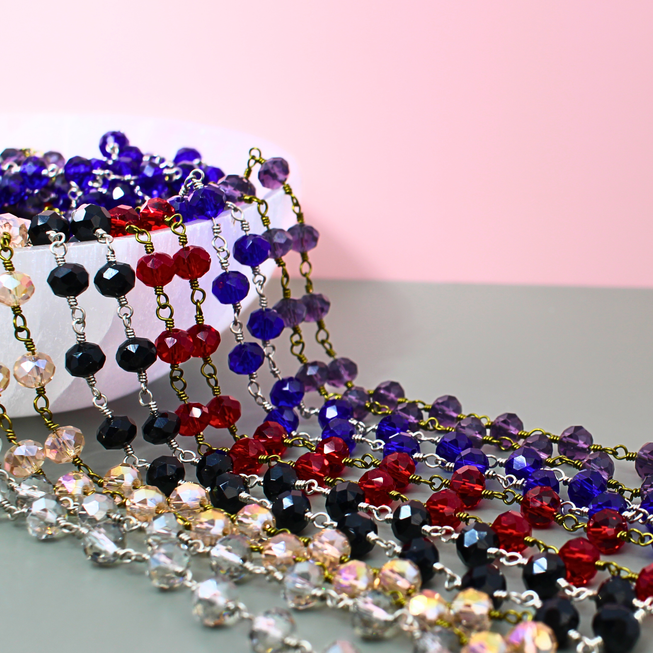 Colorful beaded necklaces on a pink and gray background