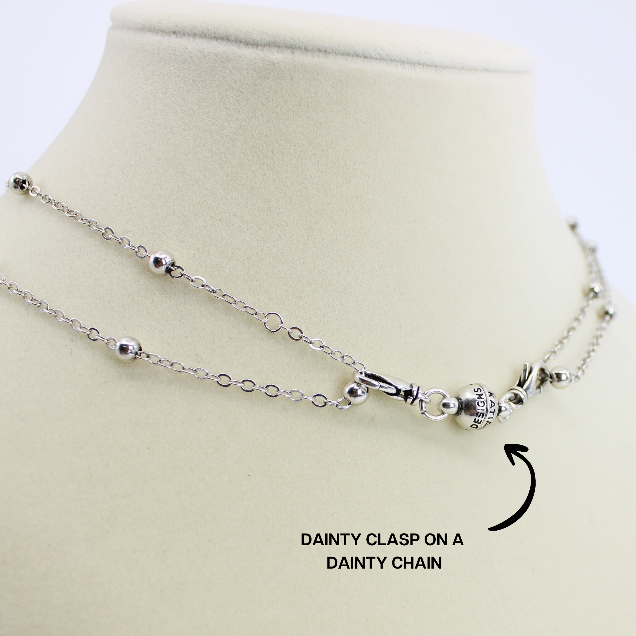 Silver necklace with a dainty clasp on a beige mannequin bust.