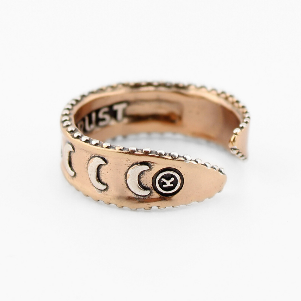 mixed-metal rings with crescent moon designs and TRUST engraved inside, each featuring adjustable bands, are shown from different angles.