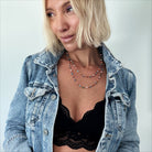 Woman wearing a denim jacket over a black lace top against a light background