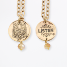Two chain necklaces with round pendants: one gold with LISTEN adorned in plated brass and small beads, the other gold featuring a face design. Each piece exudes charm, enhanced by subtle crystal accents.