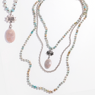 Two views of a long beaded necklace with a lotus pendant and a faceted peach quartz drop stone, with one showing the front and the other showing the back with the inscription 'HAVE FAITH'.