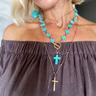 Close-up of a person wearing multiple necklaces with turquoise and gold pendants.
