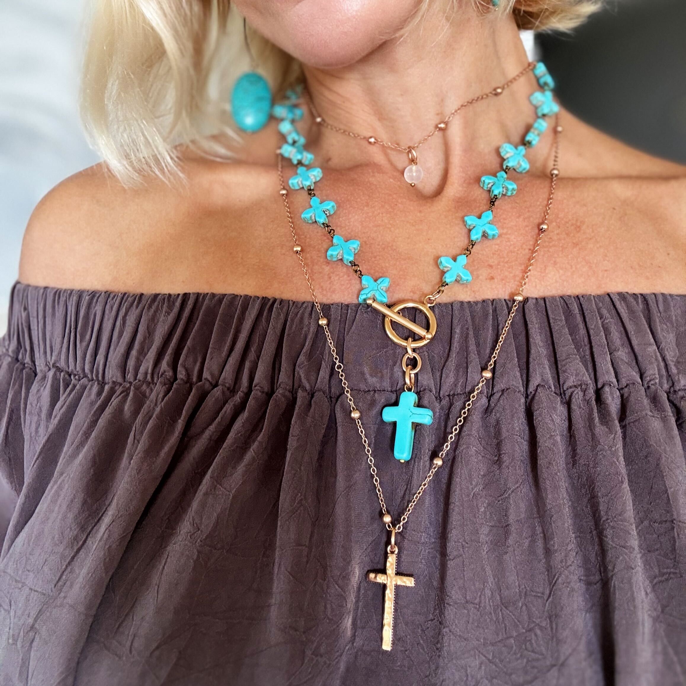 Close-up of a person wearing multiple necklaces with turquoise and gold pendants.