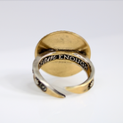 Gold and silver ring with engraved text on a white background