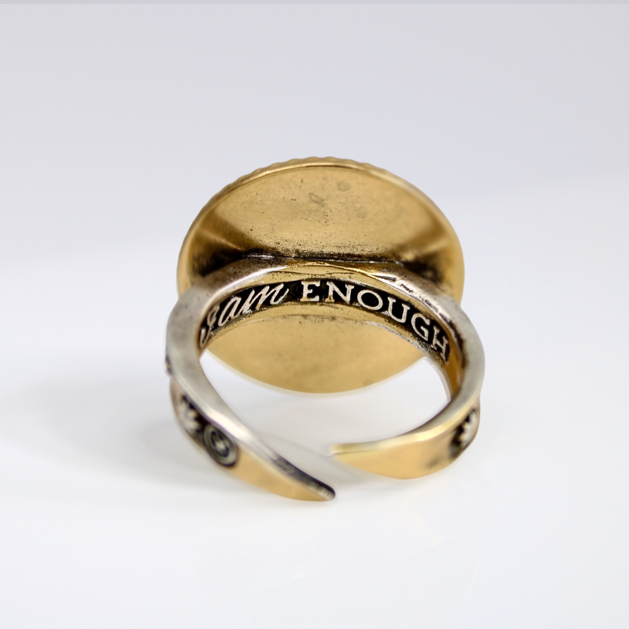 Gold and silver ring with engraved text on a white background
