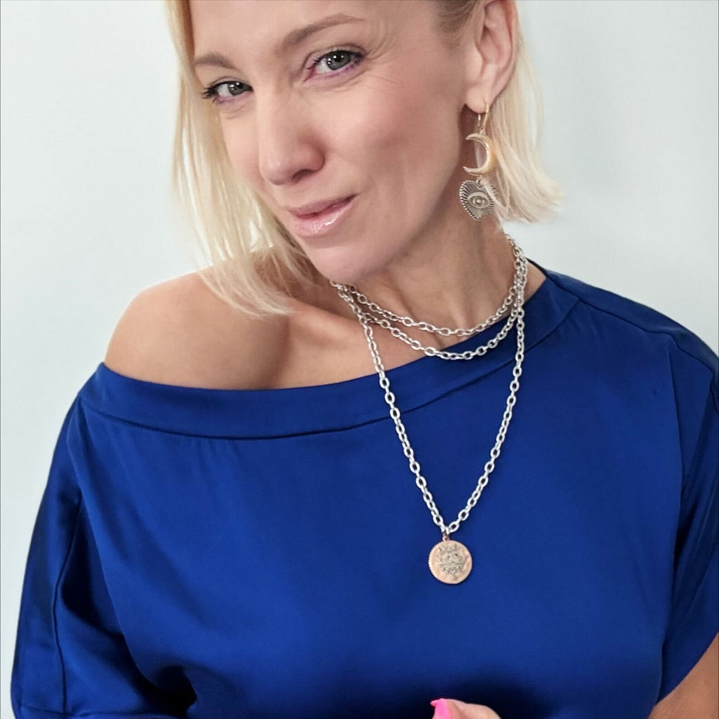 katia wearing essential - front with moon phases, the other with the word Trust inscribed. Both feature a sleek magnetic clasp for easy wear and a mixed-metal pendant design that adds elegance.