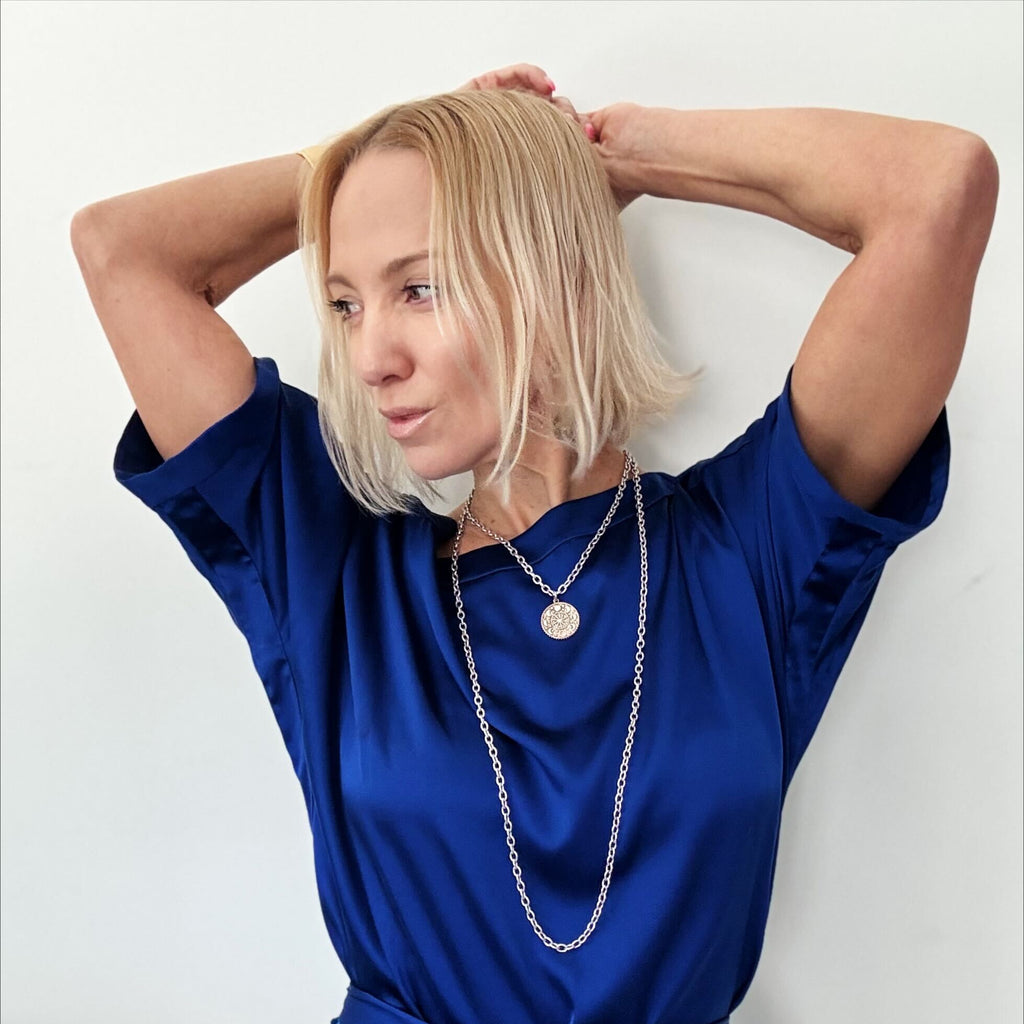 katia wearing essential - front with moon phases, the other with the word Trust inscribed. Both feature a sleek magnetic clasp for easy wear and a mixed-metal pendant design that adds elegance.