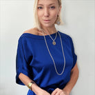 katia wearing essential - front with moon phases, the other with the word Trust inscribed. Both feature a sleek magnetic clasp for easy wear and a mixed-metal pendant design that adds elegance.